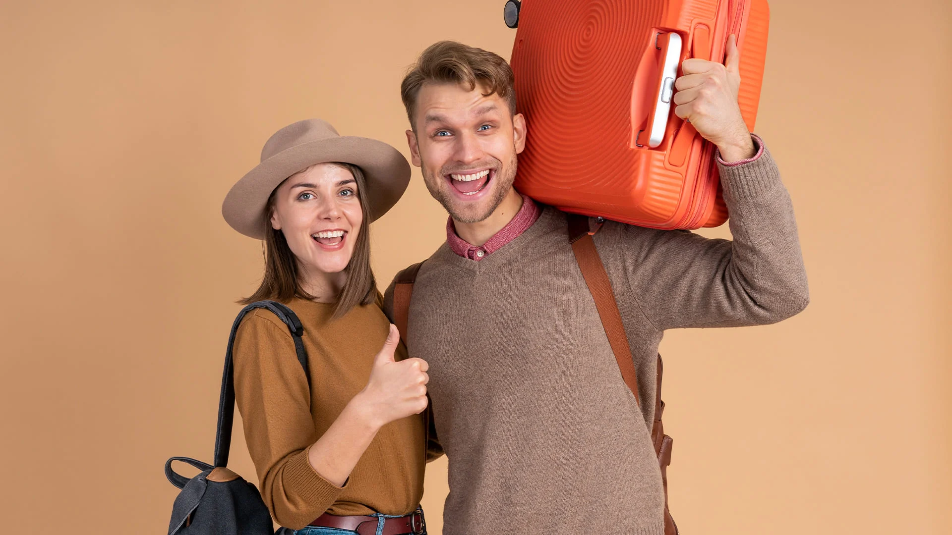 Happy couple with travel suitcases and orange background